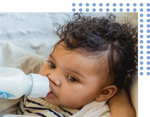 baby with black curly hair drinking from a bottle